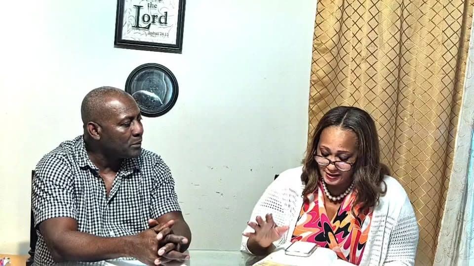 Pastor Heldin and Apostle Sctonda Gordon at a table with an open Bible during a “15 Minutes with Jesus” broadcast