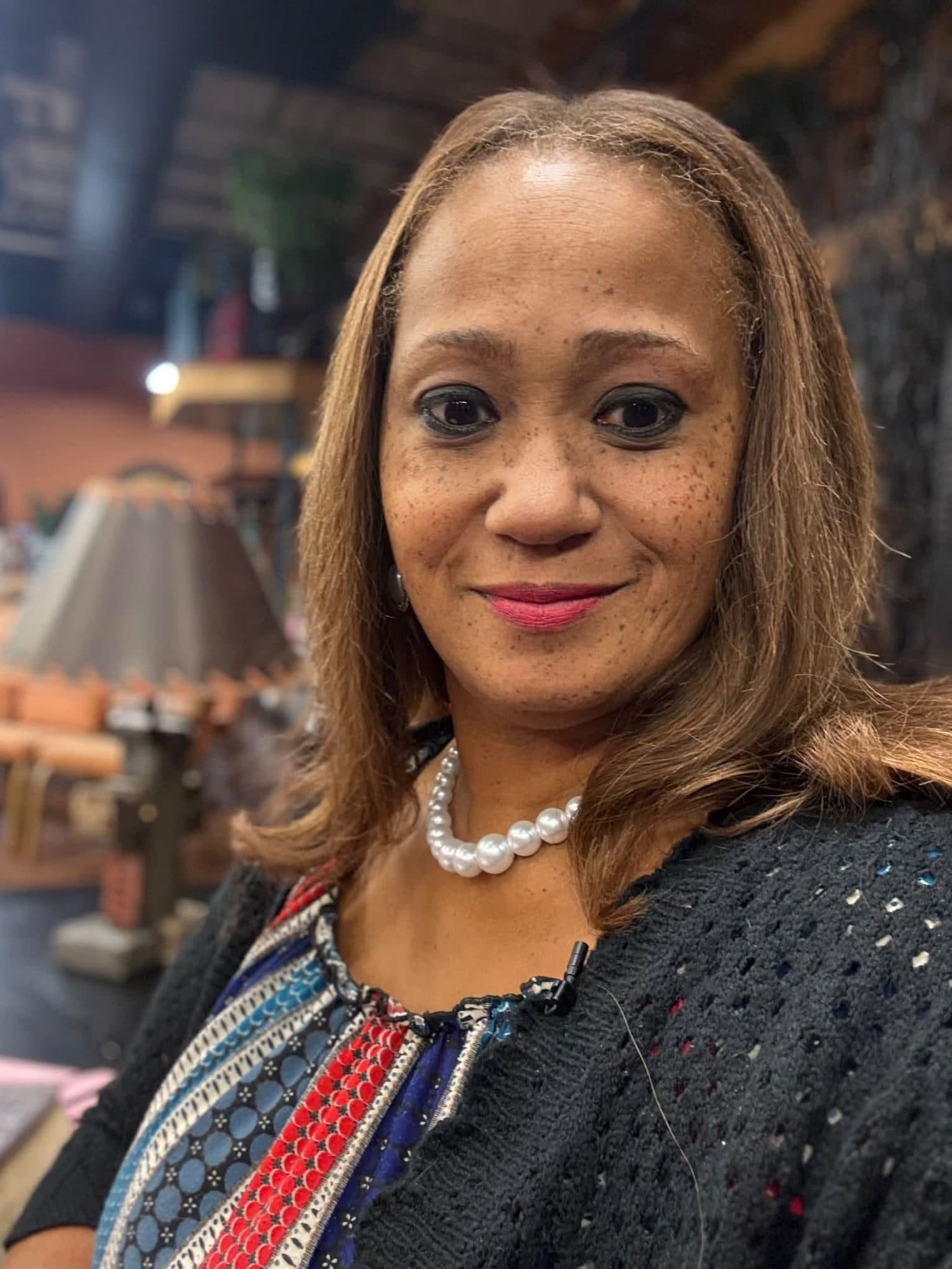 Apostle Dr. Sctonda Kelly Gordon in a pearl necklace, wearing a lapel microphone on a television set