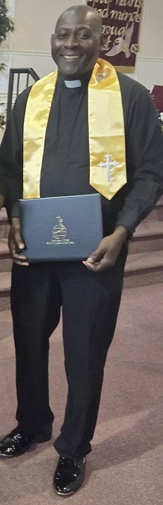A graduate’s gold stole with a white cross, and a blue diploma cover